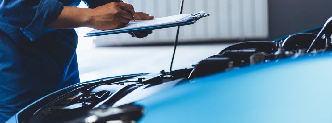 Mechanic checking a vehicle under the hood.