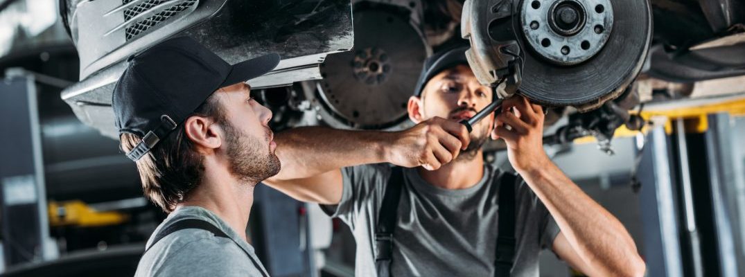 Two technicians provide maintenance to a car.