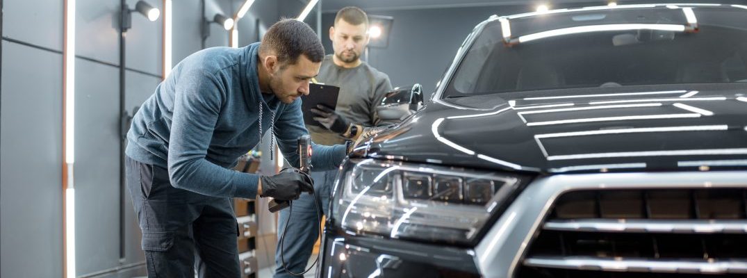 Two inspectors look over a car.