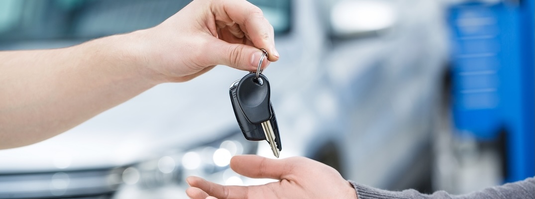 A salesman passes the keys to a car to the new owner.